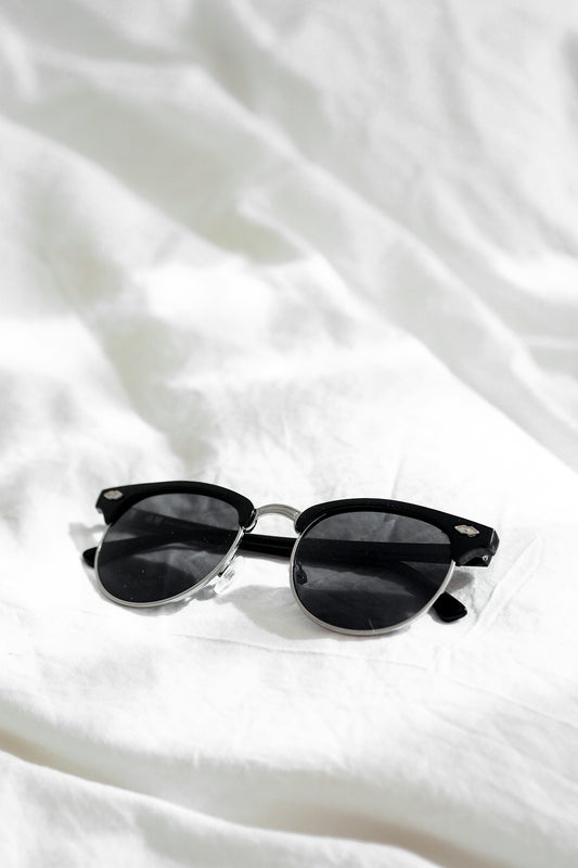 black framed sunglasses on white textile